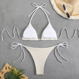 Detail of off-white crochet bikini set with halter top and side-tie bottoms on beach props