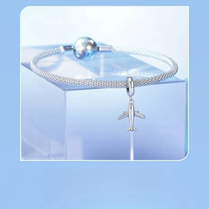 Detailed view of an S925 silver mesh bracelet featuring a delicate airplane travel charm