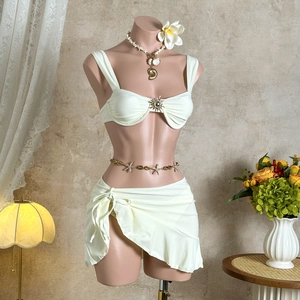 Détail du haut de bikini crème avec boucle dorée et jupe de plage assortie