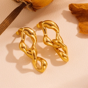 Detailaufnahme goldener gedrehter Blatt-Ohrhänger auf einem Vintage-Strukturhintergrund
