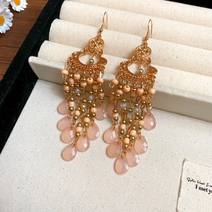 Detail of vintage gold tassel earrings with pink teardrop gems in a jewelry box