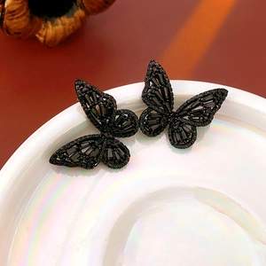 Macro shot of black zircon butterfly earrings featuring intricate hollowed design