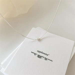 Detailed close-up of 925 sterling silver chain with a polished cube pendant on paper
