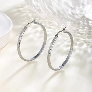 Macro shot of silver textured hoop earrings with intricate geometric pattern detailing