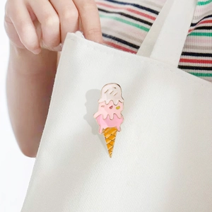 Detailed view of an ice cream enamel pin with pink and white glaze on a canvas bag