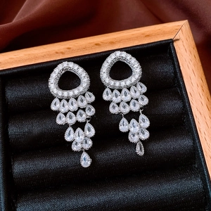 Macro shot of silver tassel earrings with round and pear-cut zircon in a velvet box
