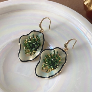 Macro detail of irregular gold petal earrings with green enamel floral stamens