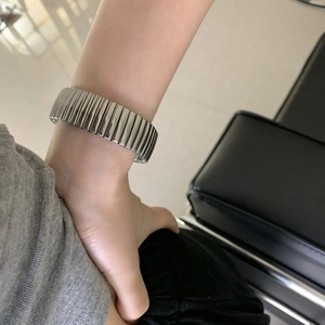 Bracelet élastique en acier titane argenté avec texture métallique striée sur le poignet