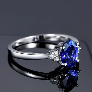 Elegant silver ring with oval royal blue gemstone and side stones on black background