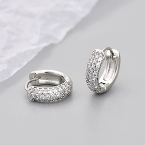 Close-up of silver huggie earrings featuring three rows of micro-pave set cubic zirconia