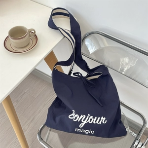 Détail du sac cabas bleu avec lettrage Bonjour magic et bandoulière rayée
