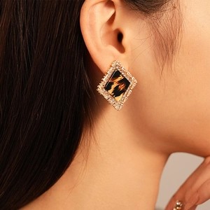 Close-up of diamond-encrusted leopard print resin stud earrings on a model's ear