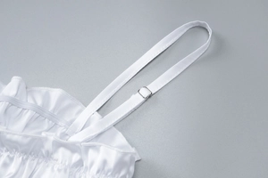 Detail of adjustable thin straps and elastic ruffled neckline on a white silky top
