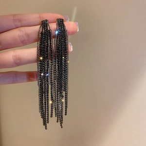 Detailed close-up of long black tassel earrings with shimmering rhinestones and metal finish