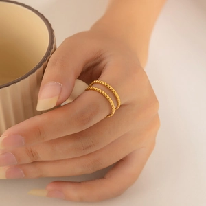 Macro detail of minimalist gold double-layered beaded ring on a female hand