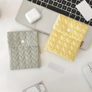 Close-up of heart-quilted fabric storage pouches in sage green and lemon yellow with snaps
