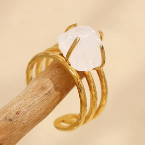 Detail of 18K gold plated multi-layer ring with large white natural stone on wood stand