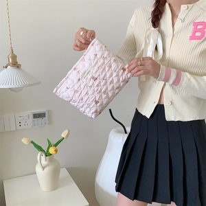 Pink heart quilted cosmetic bag held by a model in a cozy lifestyle setting