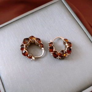 Macro detail of vintage gold plated hoop earrings with amber crystals on silk