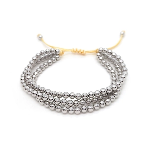 Detailed view of triple-layered silver bead bracelet with adjustable yellow drawstring cord