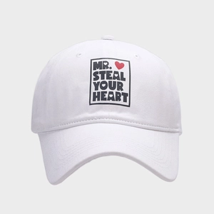 Close-up of white cotton baseball cap featuring Mr. Steal Your Heart print with a red heart