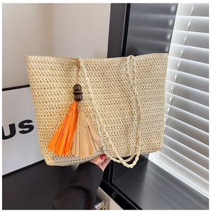 Close-up of straw tote bag featuring orange tassels and brown wooden bead charms