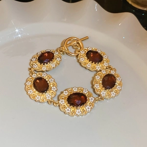 Detailed macro of vintage gold bracelet with amber gems and toggle clasp in white dish