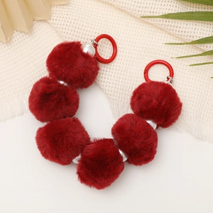 Detailed view of red plush pompom beads and pearls on a stylish mobile wrist strap