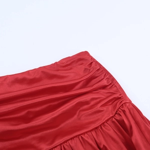 Close-up of red satin dress detailing showing elegant ruching and gathered fabric textures