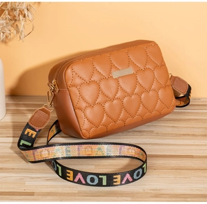 Detailed close-up of brown quilted heart bag with golden plate and LOVE strap