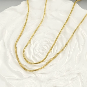 Élégant collier chaîne serpent en acier inoxydable doré 18K sur socle floral blanc