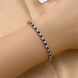 Close-up of tennis bracelet with black and white cubic zirconia on golden satin background