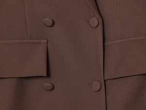 Détail d'une robe marron à manches longues avec boutons recouverts de tissu et texture