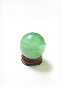 Detail of light green natural crystal sphere with textures on a wooden base
