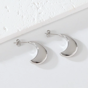 Detailed view of silver thick C-shape crescent earrings on a minimalist stone background
