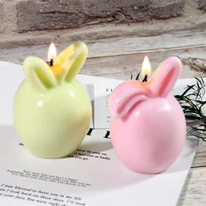Easter bunny scented candles in pink and green colors on a rustic wooden table