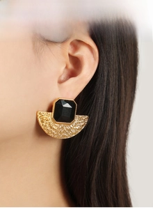 Detail of vintage fan-shaped gold-plated earring with black octagonal resin stone on model