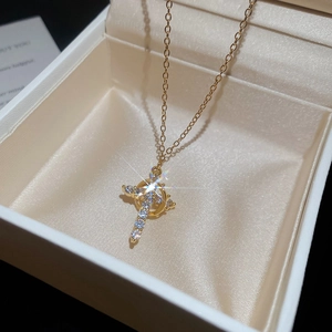 Macro del ciondolo a croce dorata con zirconi cubici su una collana a catena sottile