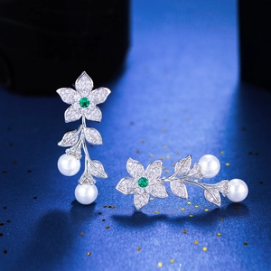 Close-up of luxury leaf earrings with green crystals, zircons and white pearls