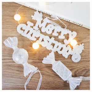 Dettaglio di decorazioni bianche glitterate e targa Merry Christmas su tavolo in legno
