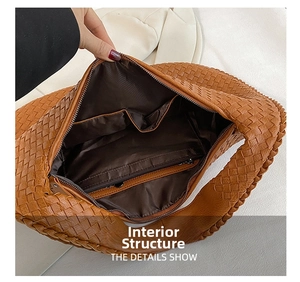 Detail view of woven handbag interior featuring zip pocket and deep brown lining