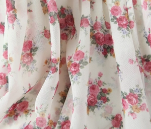 Close-up of lightweight chiffon fabric with pink floral print and natural drape