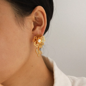 Close-up of golden sunflower earring with pearl center and crystals worn by a model