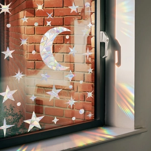 Close-up of moon and stars rainbow suncatcher film projecting light on a brick wall