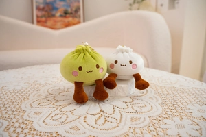 Detail of cute steamed bun plush keychains with smiling faces on white lace fabric