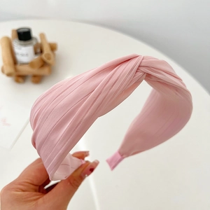 Close-up of pink pleated fabric headband showing soft texture and elegant design