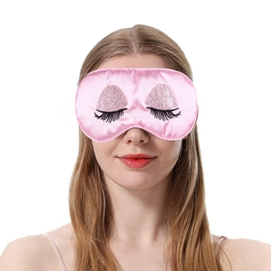 Close-up of pink silk sleep mask with sequin eyeshadow and black eyelash embroidery