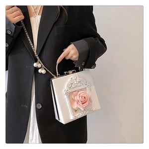 Close-up of white embossed floral handbag with pink rose accents and pearl chain