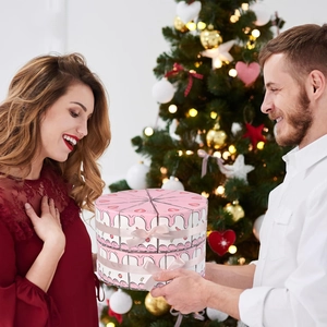 Pink triangular cake-shaped gift boxes with ribbons shown in a festive gifting scene