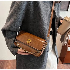 Close-up of brown vintage crossbody bag with golden metal buckle and chain decoration
